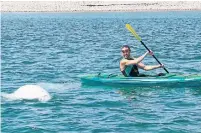  ?? THE CANADIAN PRESS ?? Bernie Lamey paddles around two beluga whales that have drawn crowds to an area off Ingonish Beach in Cape Breton, N.S.