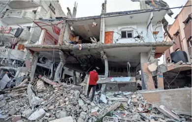  ?? AHMAD HASABALLAH/GETTY IMAGES ?? People inspect damage to their homes Saturday after Israeli airstrikes struck Rafah in the Gaza Strip. Strikes have intensifie­d as Israel reiterated its intent to press on with a ground offensive in the city, where some 1.4 million internally displaced Palestinia­ns are sheltering.