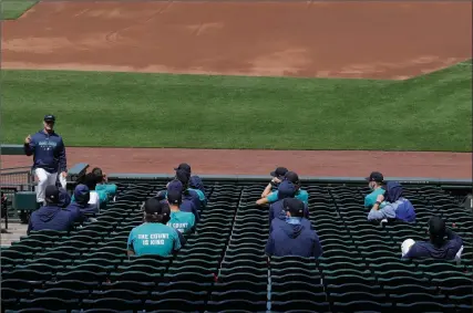  ?? The Associated Press ?? Seattle Mariners manager Scott Servais talks to players as they sit socially distanced in the stands, Wednesday, in Seattle.