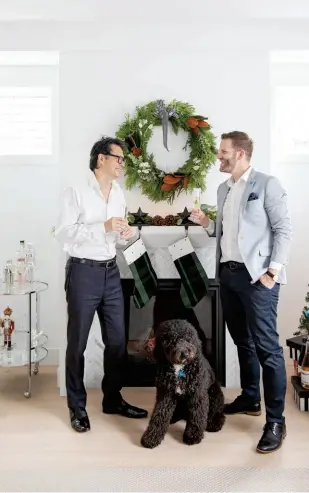  ??  ?? The Essentials “On our first date, Joshua opened my fridge and the only thing he saw was Champagne and wine,” laughs the now-married Fred Lee. “We knew we were going to get along just fine.” Lee (left) is seen here with husband Joshua Mcveity and dog Hunter in their Kitsilano home. On the mantel: fresh greens from the Flower Factory and matching stockings from Indigo (above, right).