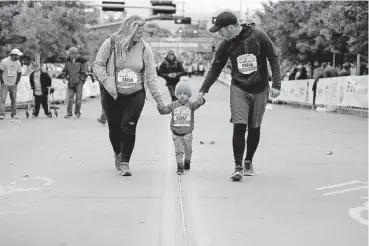  ?? [PHOTO BY BRYAN TERRY, THE OKLAHOMAN] ?? Royce and Keri Young walk with their son Harrison, age 2, during the children’s portion of the marathon on Sunday. The Youngs participat­ed in Sunday’s event in honor of their baby Eva, who was stillborn.