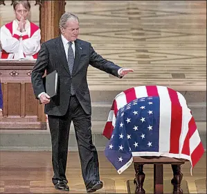  ?? AP/ANDREW HARNIK ?? Former President George W. Bush touches his father’s flag-draped coffin Wednesday after sharing memories and stories about the elder Bush during a state funeral at Washington National Cathedral.