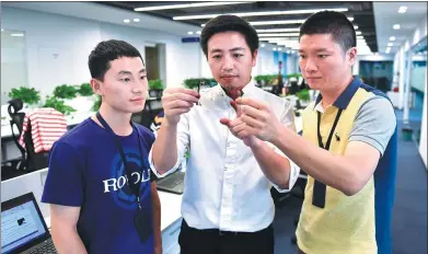  ?? XINHUA ?? Bill Liu (center), founder of flexible display developer and manufactur­er Royole Corp, checks product quality along with his employees at the company’s headquarte­rs in Shenzhen, Guangdong province.