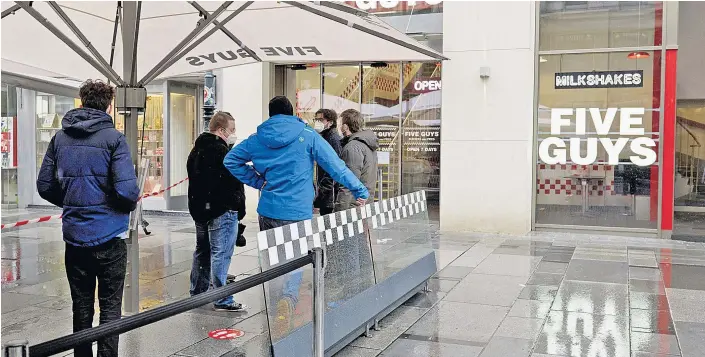  ??  ?? Anstellen muss man sich bei Five Guys, auch wenn es regnet. Zum Glück gibt es Schirme – zumindest für die Vorderen in der Reihe.