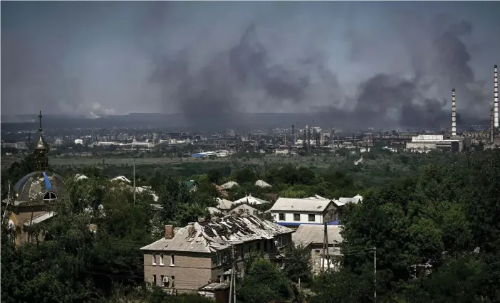  ?? FOTO: ARIS MESSINIS/LEHTIKUVA/AFP ?? En skadad byggnad i Lysychansk och svart rök stiger upp från den närliggand­e staden Severodone­tsk efter strider mellan ryska och ukrainska trupper i regionen Donbas i östra Ukraina den 9 juni 2022. – Ryska styrkor har i veckor koncentrer­at sin eldkraft på Severodone­tsk och dess systerstad Lysychansk på andra sidan floden. Arkivbild.