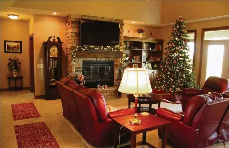  ??  ?? Multiple windows in the great room face the long veranda. Built-in bookcases sit at one side of the stone fireplace, which is accented by a rustic mantel.