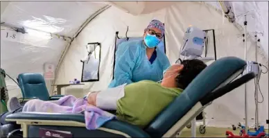  ?? PHOTO HEIDI DE MARCO, CALIFORNIA HEALTHLINE ?? Sylvia Cervantes, a medical assistant, assesses a patient who might have COVID-19. Cervantes usually works in the oncology department but was assigned to help in the triage tent.