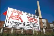  ??  ?? A sign advertisin­g the auction of the Peerless Woolen Mills property has been raised in front of the mill.