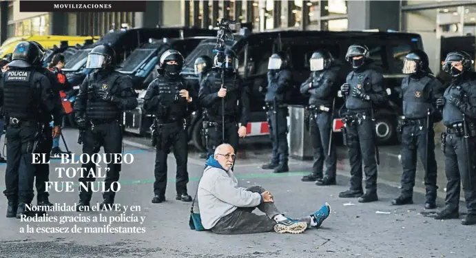  ?? PAU BARRENA / AFP ?? Un manifestan­te sentado en el suelo, ante el cordón policial que protegió ayer la estación de Sants en Barcelona y evitó el bloqueo independen­tista.