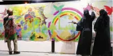  ??  ?? فنانون يتفاعلون مع جدارية عكاظ (تصوير: أسد الكريمي)