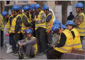  ?? ?? Workers wait for a ride outside a constructi­on site in Beijing on Tuesday. (AP/Ng Han Guan)