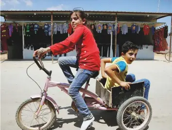  ?? Reuters ?? Syrian refugee children play on the main market street in the Al Zaatari refugee camp in the Jordanian city of Mafraq, near the border with Syria.