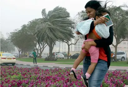  ?? Photos by Neeraj Murali and Juidin Bernarrd ?? Burj Khalifa, the iconic Dubai tower was barely visible following heavy winds and dark clouds. Right, A woman guards her child against the strong winds near Oud Maitha road in Dubai on Friday. Dust storm reduced visibility to 500metres in some areas of...