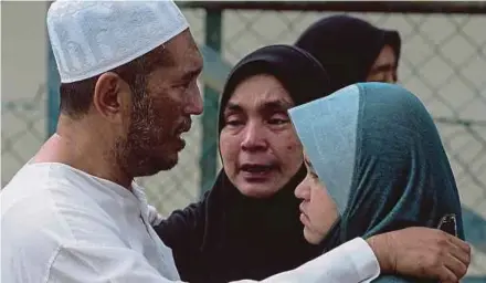  ?? [FOTO MUHAMMAD SULAIMAN/BH] ?? Zulkefli menenangka­n ibu mangsa, Wan Noor Hafidah Abu Hassan (tengah) ketika menunggu proses bedah siasat di Jabatan Forensik Hospital Tengku Ampuan Rahimah, Klang, semalam.