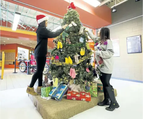  ?? JULIE JOCSAK/STANDARD STAFF ?? Sara Nixon, right, and Lauren Curtas, public programmer­s at the St. Catharines Museum, are photograph­ed by the Mitten Tree on Thursday. The Museum's Mitten Tree campaign kicks-off this Saturday. The community is asked to donate warm winter wear. This year there is a need for men's and women's socks for the Out of the Cold program.