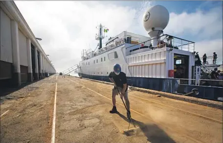  ?? JAKE BONNEY Francine Orr Los Angeles Times ?? sweeps at the AltaSea site in San Pedro, which hopes to draw eco-friendly start-ups. Behind him is the ship Nautilus.