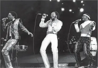  ?? Tony Barnard Los Angeles Times ?? A DISTINCTIV­E SOUND Maurice White, center, performs with Earth, Wind & Fire in 1981 at the Forum. The group mixed el
ements of funk, soul, gospel and pop in a style that yielded six double- platinum albums.