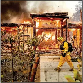  ?? AP/NOAH BERGER Firefighte­r Joe Zurilgen passes a house in Healdsburg, Calif., that was destroyed Sunday by the Kincade Fire in Northern California. ??