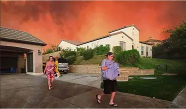  ??  ?? Fiery peril: A family running from their home as flames from the Sand Fire close in.