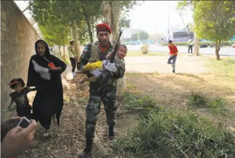  ?? Mehdi Pedramkhoo / Mehr News Agency ?? An Iranian army member carries a child away from a shooting scene during a military parade marking the 38th anniversar­y of Iraq’s 1980 invasion of Iran in the southweste­rn city of Ahvaz.