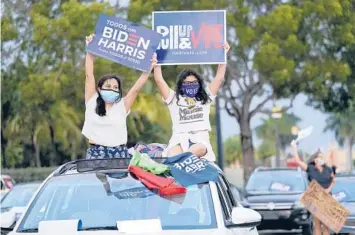  ?? LYNNE SLADKY/AP 2020 ?? Claudia Cedillos, left, waves signs with her daughter, Montserrat, before a campaign rally for then-Democratic presidenti­al candidate Joe Biden in Miami. Some who backed Biden for president are now unhappy with him.