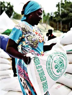  ?? ?? ▴A woman receives a bag of food from the government during the distributi­on of food items by the government to cushion the high cost of living in Abuja, Nigeria.