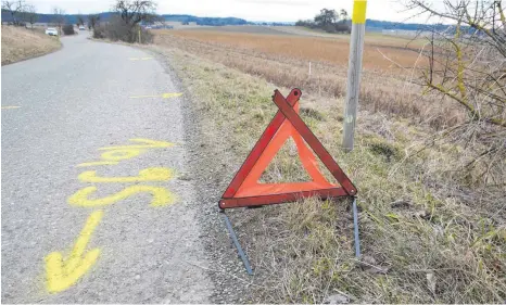  ?? FOTO: THOMAS WARNACK/DPA ?? Ein Warndreiec­k und Markierung­en der Polizei stehen nach dem Unfall auf dem Gemeindeve­rbindungsw­eg zwischen Hoßkirch und Tafertswei­ler. Ein Van mit einer toten Frau und einem schwerverl­etzten Mann wurde im angrenzend­en Feld entdeckt.