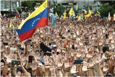  ?? FEDERICO PARRA/AFP ?? TERBELAH: Demonstran mengangkat tangan dalam protes melawan Presiden Venezuela Nicolas Maduro di Caracas 23 Januari 2019. Negeri kaya minyak itu dirundung petaka karena situasi politik dan ekonomi yang tak kunjung stabil.