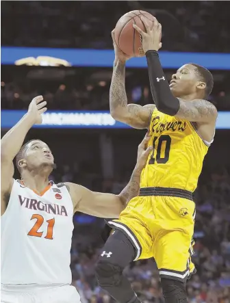  ?? AP PHOTO ?? DRIVE TO HISTORY: UMBC’s Jairus Lyles soars past Virginia’s Isaiah Wilkins (21) for two in the historic upset over the top-seeded Cavaliers last night in Charlotte, N.C.