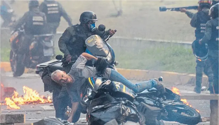  ?? AFP ?? Violencia. Un manifestan­te con su moto cae al piso al intentar eludir a miembros de la Guardia Nacional Bolivarian­a, que ayer reprimiero­n la protesta contra Maduro en Caracas.