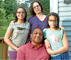  ??  ?? Andrew Grant-Thomas sits in his backyard with his partner, Melissa, and daughters. — The Washington Post photo by Philip Keith