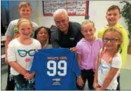  ?? FILE PHOTO ?? In this file photo, Rich Johns, center, presents a “99” T-shirt to children at Tanglewood Elementary School in South Glens Falls. His “99” concept encourages kids to treat others with kindness all the time.