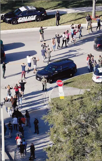  ??  ?? Students hold their hands in the air as they are evacuated by police from Marjory Stoneman Douglas High School in Parkland, Florida on Feb 14, after a shooter opened fire on the campus. (AP)