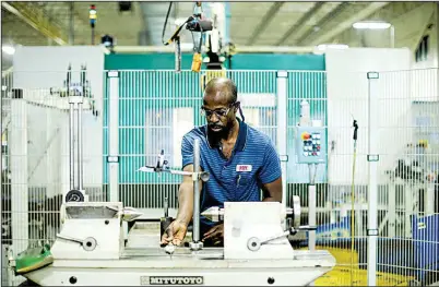  ?? Bloomberg News/TRAVIS DOVE ?? A systems operator works last month alongside robots that manufactur­e gears at the Southern German Electric Motor Works-Eurodrive Inc. factory in Lyman, S.C.