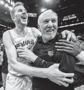  ?? William Luther / Staff photograph­er ?? Gregg Popovich can’t resist a smile as he’s mobbed by Spurs center Jakob Poeltl and the rest of his players after earning his record 1,336th win Friday night.