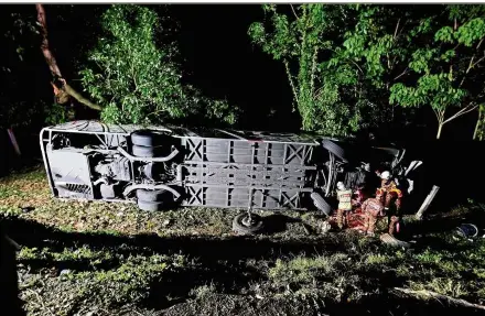  ??  ?? Tragic end: Fire and Rescue Department personnel preparing to winch the bus from the ravine after it crashed near Taiping. — Bernama