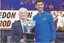  ?? AARON FAVILA/ASSOCIATED PRESS FILE PHOTO ?? Serbia’s Novak Djokovic, right, presents a trophy to Rod Laver in 2019 during the 50th anniversar­y celebratio­n for the Australian Open and Laver’s second Grand Slam.