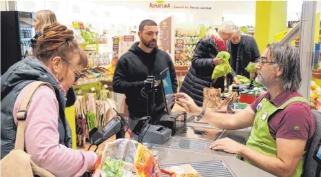  ?? FOTO: JULIA BAUMANN ?? Silvia Zintner (links) kauft am Donnerstag­vormittag im neuen Alnatura-Markt ein. An der Kasse sitzt Roland Rieser, der ab jetzt im Lindauer Bio-Supermarkt arbeitet.