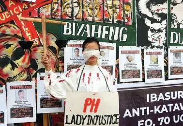  ??  ?? A PROTESTER acts as lady injustice, as rights groups call on justice for slain colleagues during a protest rally in observance of the Internatio­nal Human Rights Day at Freedom Park on Tuesday. BING GONZALES