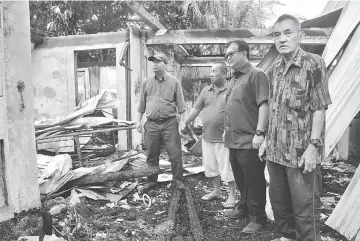  ??  ?? (From left) Kapit District Officer Elvis Didit, Siban, Nanta and MRC Kapit treasurer Ling Thian Ing examine the damaged caused by the fire.