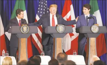  ?? MARTIN MEJIA/AP ?? President Donald Trump, center, reaches out to Mexico's President Enrique Pena Nieto, left, and Canada's Prime Minister Justin Trudeau as they prepare to sign a new United States-Mexico-Canada Agreement on Friday.