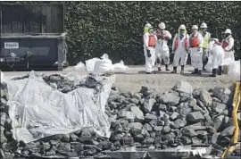  ?? Don Leach Times Community News ?? A CLEANUP CREW hauls bags of crude oil from the Talbert Marsh ecological reserve in Huntington Beach, days after the spill of an estimated 25,000 gallons.