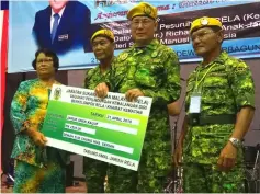  ??  ?? Riot (second right) hands over a mock cheque to a widow of a Rela member as (from right) dinner organising chairman Albert Mintol and Rini look on.