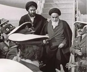  ?? AFP PIC ?? Ayatollah Ruhollah Khomeini (centre) exiting an airplane during his return from exile in France to Teheran on Feb 1, 1979.