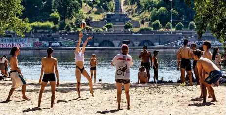  ?? ?? Having a ball: a group make the most of the weather and play a volleyball match in yesterday’s sunshine