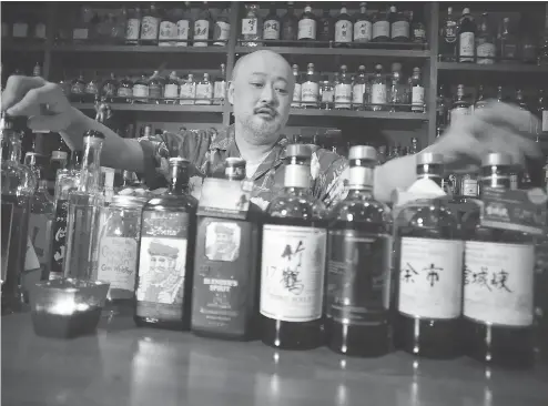  ?? EUGENE HOSHIKO / THE ASSOCIATED PRESS ?? Owner and bartender Atsushi Horigami of Tokyo’s Zoetrope, which is famed among lovers of Japanese whisky. “Japanese whisky has an unpredicta­bility that makes it fun, and the highly skilful Japanese blenders have created a subtle taste with an...