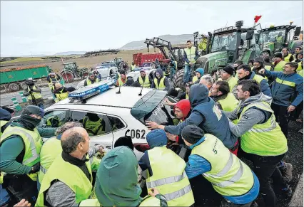  ?? ?? Pamplona. Varios agricultor­es mueven coches de la Guardia Civil ayer para acceder a esta ciudad española.