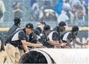  ?? BRIAN CASSELLA/CHICAGO TRIBUNE ?? The grounds crew puts the tarp on the field as a rain delay begins in the third inning of a game between the White Sox and Seattle Mariners on June 26 at Guaranteed Rate Field.