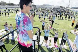  ?? TAIMY ALVAREZ/STAFF PHOTOGRAPH­ER ?? Michael Gorlano, a certified yoga instructor and Boca High School student who is autistic, leads hundreds of students in a yoga class on the school’s football field.