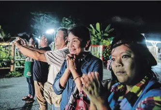  ?? LAUREN DECICCA GETTY IMAGES ?? Onlookersc­heer as ambulances take boys rescued from a cave in northern Thailand to hospital in Chiang Rai.